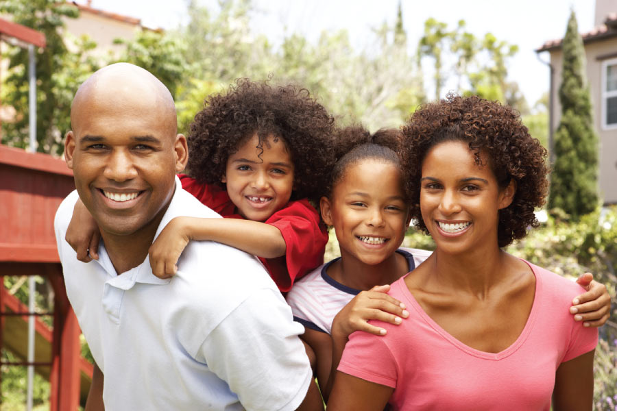 Mom and Dad give their son and daughter piggyback rides in the backyard and protect them from coronavirus